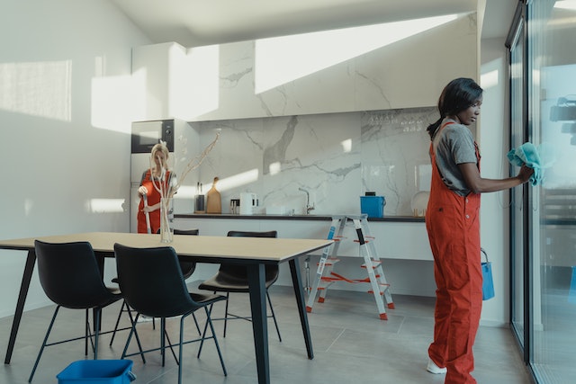 two people in orange overalls cleaning office kitchen